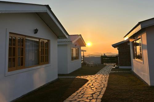 a house with the sunset in the background at Saanjh Cottages - Hotel in Bir Billing in Bīr