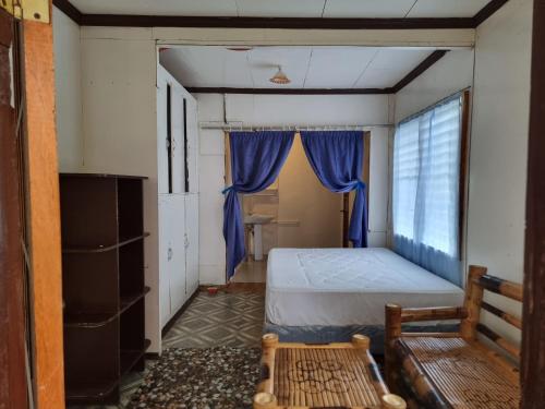 a bedroom with a bed and a window at Penoria's lodge kubo in Mambajao