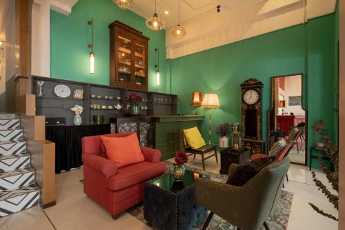 a living room with green walls and a clock at Chinoir Boutique Phuket Town in Phuket