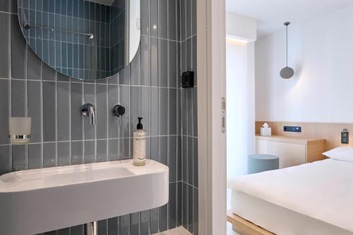 a bathroom with a sink and a mirror at Twinn Downtown Piraeus, Santikos Collection in Piraeus