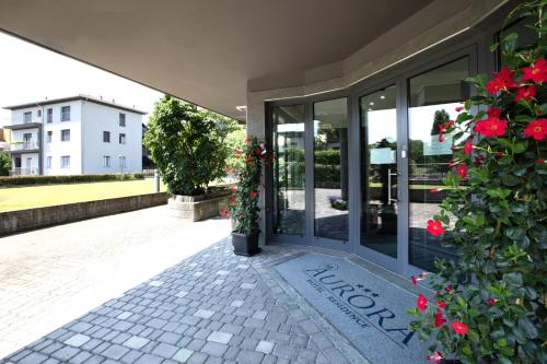 a entrance to a building with red flowers at Hotel Residence Aurora in Paderno Dugnano