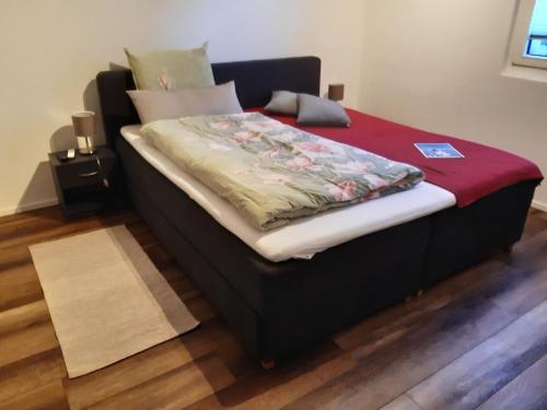 ein Bett in einem Zimmer mit einer roten Decke darauf in der Unterkunft Studio "Chüngelhoschet" in Näfels