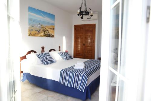 a bedroom with a bed with blue and white striped sheets at Brasilia in Chipiona