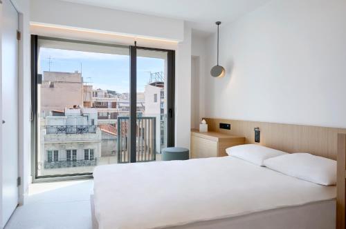 a bedroom with a white bed and a large window at Twinn Downtown Piraeus, Santikos Collection in Piraeus