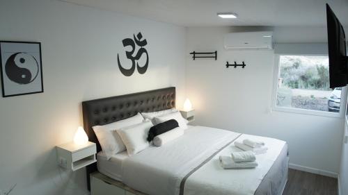 a white bedroom with a large bed with white pillows at Ecos de Mar Refugios in Puerto Pirámides