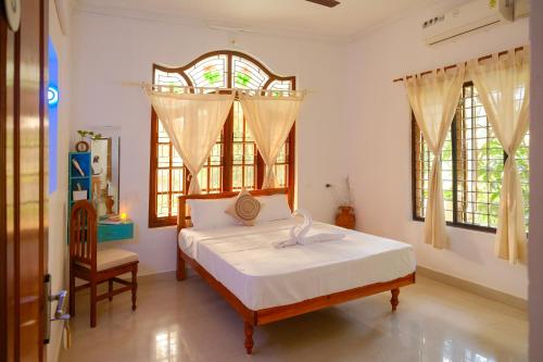 a bedroom with a bed and a chair and windows at Lakshmi Ayurveda Retreat in Kovalam
