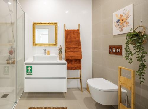 a bathroom with a sink and a toilet and a mirror at Aurora do Furadouro II in Ovar
