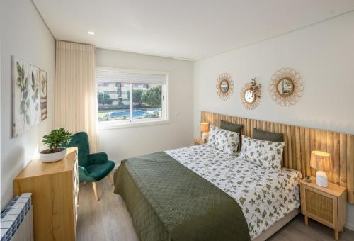 a bedroom with a bed and a green chair at Aurora do Furadouro II in Ovar