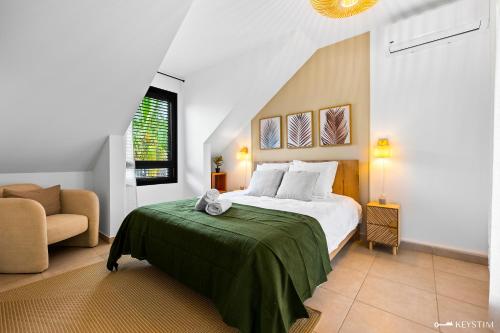 a bedroom with a bed with a green blanket at Koté La Savan' in Saint-Paul