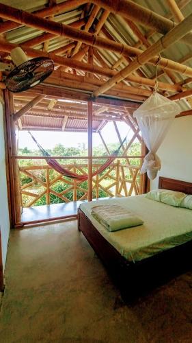 a bedroom with a bed and a large window at Casa de Guadua in Dibulla