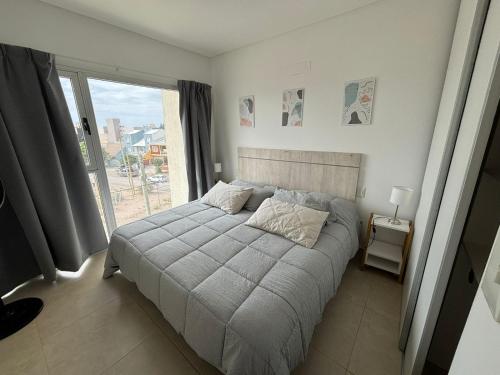 a bed in a bedroom with a large window at Arenas Gutyn Ebrill in Puerto Madryn