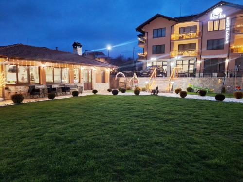 a house with a lawn in front of a building at Perla Guest House in Dospat