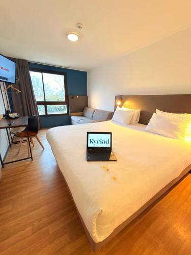a bedroom with a bed with a laptop on it at Kyriad Blois Sud - Vineuil in Vineuil