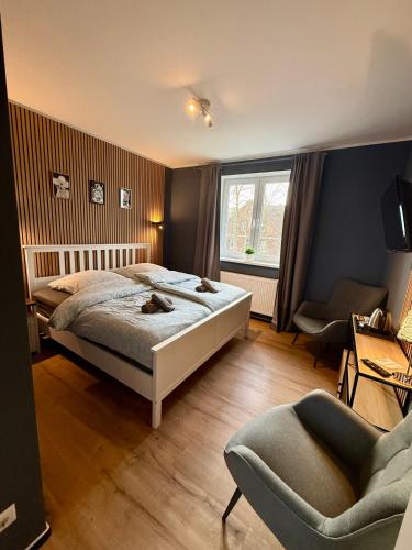 a bedroom with a bed and a chair and a window at Die Schlafstube - Boutiquehotel in Neuharlingersiel