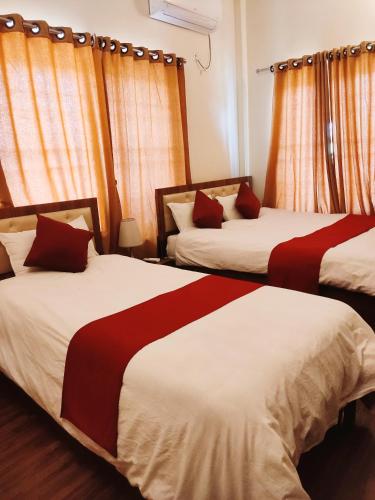 a bedroom with two beds with red and white sheets at Hotel Lisne jungle land in Bharatpur