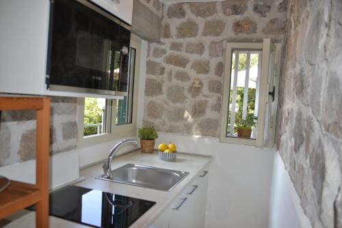 a kitchen with a sink and a stone wall at Casa William in Porto Azzurro