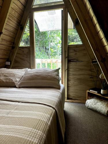 a bedroom with a bed and a large window at Romantic Cozy Serene A Frame Mountain Cabin in Cayey