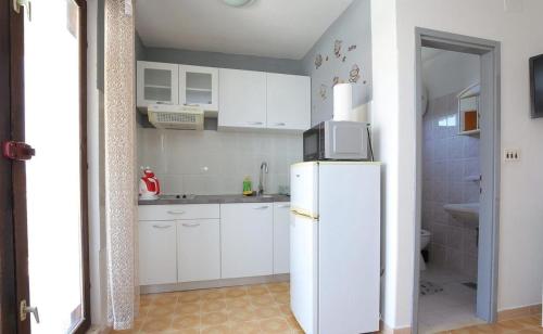 a kitchen with white cabinets and a white refrigerator at Apartmani Suzi in Slatine