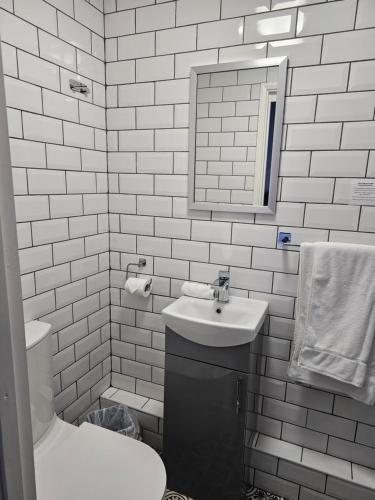 a bathroom with a sink and a toilet and a mirror at The Ivernia hotel in Skegness