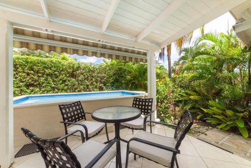 Un porche con sillas y una mesa y una piscina. en 82 Cherry Avenue, en Saint James