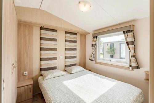 a small bedroom with a bed and a window at Camping Papillon Kinrooi 113 in Kinrooi