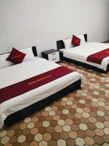 two beds with red pillows in a room at Mũi Si Homestay Cửa Tùng in Vĩnh Bang