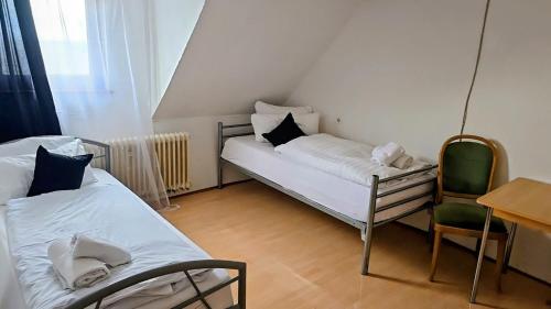 a small room with two beds and a chair at Monteurzimmer Nähe Pforzheim in Engelsbrand