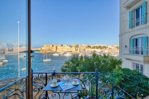 a table on a balcony with a view of the water at Charming City Stay close to Seafront in Birgu