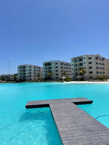 a swimming pool with a wooden dock in front of some buildings at Bluu Habitat Lagoons 206 in Mazatlán