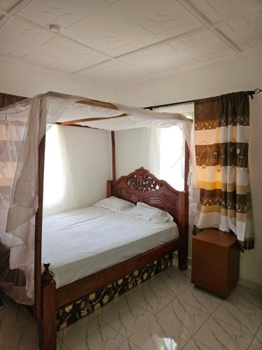 a bedroom with a canopy bed and a window at Malindi Jerere BnB in Malindi