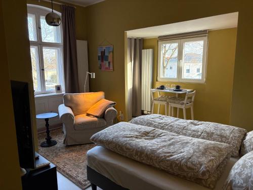 a bedroom with a bed and a chair and windows at Gemütliches Studio am Stadtrand Haustierfreundlich in Berlin