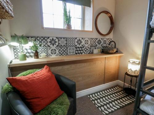 a living room with a chair and a mirror at The Boat House - Port Eynon in Swansea