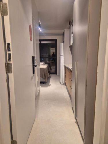 a hallway of a kitchen with a sink and a refrigerator at Apto Stúdio Liberdade novíssimo in São Paulo