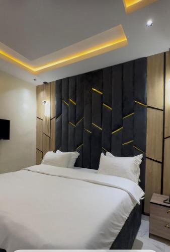 a bedroom with a large white bed with a black headboard at Moor Times Hotel in Benin City