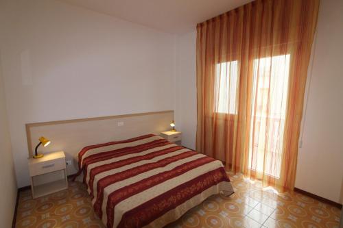 a bedroom with a bed and a large window at Residence Rondinelle in Lignano Sabbiadoro