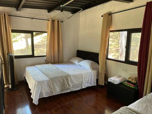 a bedroom with a bed and two windows at Blue Dream in Los Altos de Cerro Azul