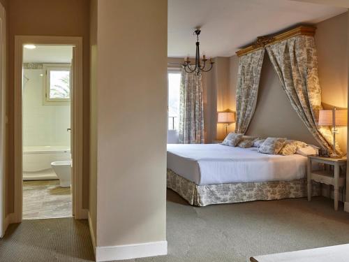a bedroom with a bed and a bathroom with a tub at Hotel Zubieta in Lekeitio