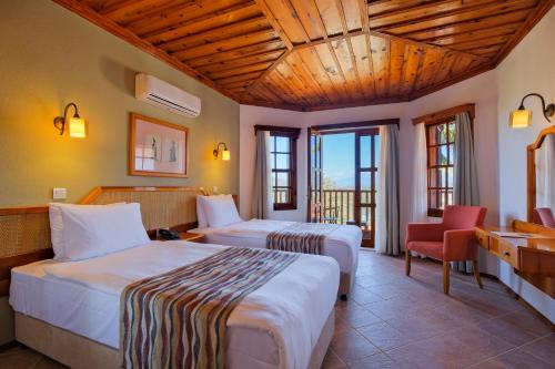 a hotel room with two beds and a chair at Montana Pine Resort - All Inclusive in Oludeniz