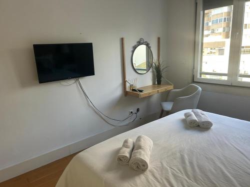 a bedroom with a bed and a tv on the wall at suites Lisboa areeiro in Lisbon