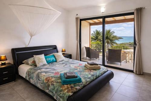 a bedroom with a bed with a view of the ocean at Duplex Palm Beach - Plage et Rando in Le Gosier