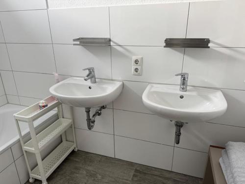 a bathroom with two sinks on a white tiled wall at Dream Holiday Haus in Uetersen