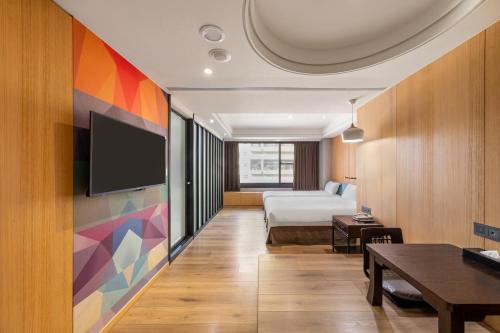 a hotel room with a bed and a flat screen tv at CHECK inn Taichung Wenxin Zhongqing in Taichung
