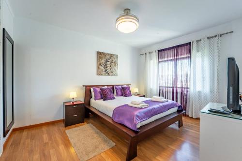 a bedroom with a bed with purple pillows and a tv at Cozy and Quiet Spacious Flat in Oliveira do Douro