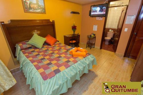 a bedroom with a bed with a blanket and a tv at Hotel Gran Quitumbe in Quito