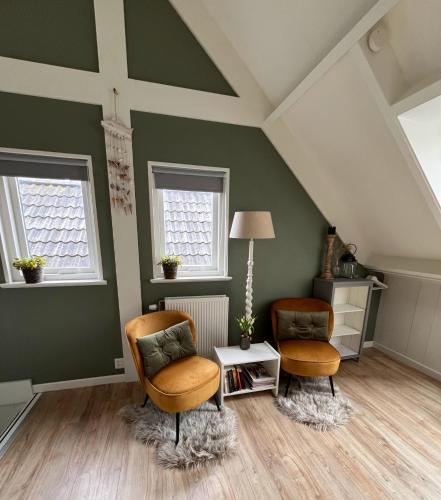 two chairs and a table in a room with green walls at bed bij zee in Westkapelle