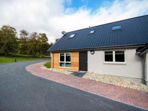 a house with a metal roof on a road at Oakwood in Aviemore