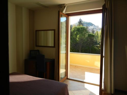 a bedroom with a door open to a balcony at Hotel Dei in Cascia