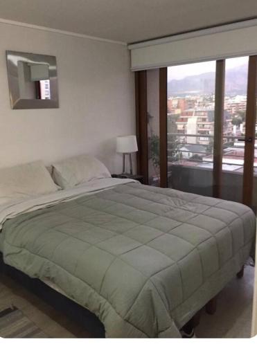 a bedroom with a large bed with a large window at Plaza ñuñoa in Santiago