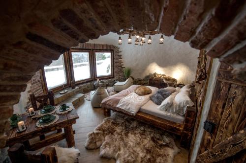 a bedroom with a bed and a table and windows at Domek Hobbita z jaskinią SPA - Osada Jaworzyny in Tokarnia