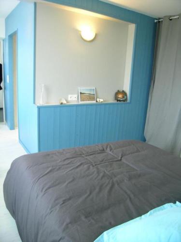 a bed in a room with a blue wall at La bergerie in Chaillevette